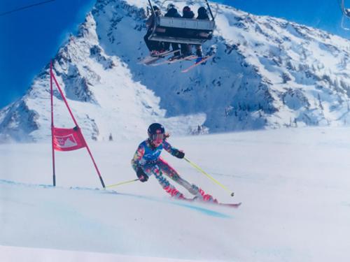 A girl racer skis fast in a super G with Crested Butte's peak behind her.